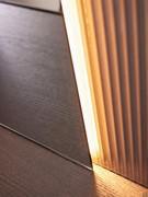 Detail der Hintergrundbeleuchtung, die durch Zurücksetzen des Spiegels um 1 cm von den plissierten Glaswänden erzielt wird