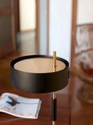 Detailansicht des zylindrischen Lampenschirms, der seitlich am Stiel befestigt ist, und des reizvollen Kontrasts zwischen Schwarz und Gold der verschiedenen Komponenten der Lampe.