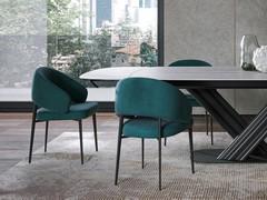 Der Stuhl zeichnet sich durch eine zurückhaltende formale Eleganz aus, die durch umhüllende Volumen definiert wird. Die Beine aus lackiertem Metall verleihen dem Möbelstück Stabilität und Leichtigkeit und sind in der Farbe individuell anpassbar.