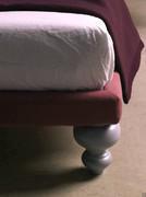 Detail of the thin upholstered and upholstered bed frame and onion-shaped wooden leg