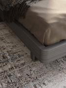 Detail of the wooden bed frame, with rounded edges and metal feet to raise it off the ground