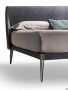 Detail of the thin metal bed frame covered in fabric with the exception of the corners at the foot of the bed and the legs that remain exposed
