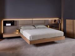 Wooden bed with California boiserie, here proposed in the version with upholstered headboard and matt lacquered side boiserie. Bed frame and bedside tables in Havana oak