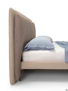 Detail of how the slim h.10 cm bed frame with high feet engages the upholstered headboard panel that reaches down to the floor