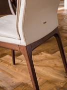 Detail of the wooden frame and leather-covered backrest with matching stitching