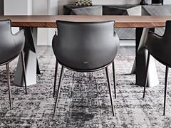 Rear view of the Rhonda chair with armrests, with its soft, enveloping shapes contrasting with the slim, embossed metal frame