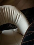 Detail of the curved, enveloping backrest of the Dafne chair, upholstered in leather like the rest of the chair