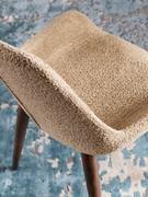 Detail of backrest and seat entirely upholstered in a bouclé fabric. The available upholstery sample book also includes more traditional fabrics and velvets, with dozens of variations