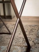 The tubular metal frame crosses over the sides, gently supporting the top. Bronze or titanium are the available finishes