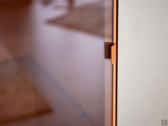 Integrated handle on lacquered metal profile. Grey transparent glass