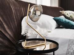 The profile of the brushed brass frame rises lightly upwards to the smoked crystal glass shade