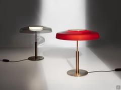 Dora is available in the model with a smoked lampshade and black metal body or in the red blown glass variant with a gold satin frame