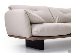 Detail of the upholstered armrest with soft fabric cover folded inwards. Feature that accentuates the generous shapes of the ensemble