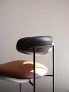 Detail of the precious workmanship of the curved solid ash wood backrest and the metal rod frame supporting it at the back