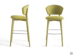 Atena stool in a version with an upholstered backrest. The lacquered beech frame rises from the legs until it delicately merges with the rear back panel