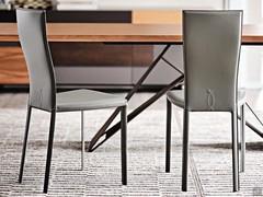 Chaises Nina revêtues de cuir de différentes couleurs, avec dossier haut et pieds revêtus d'un tissu assorti à l'assise.
