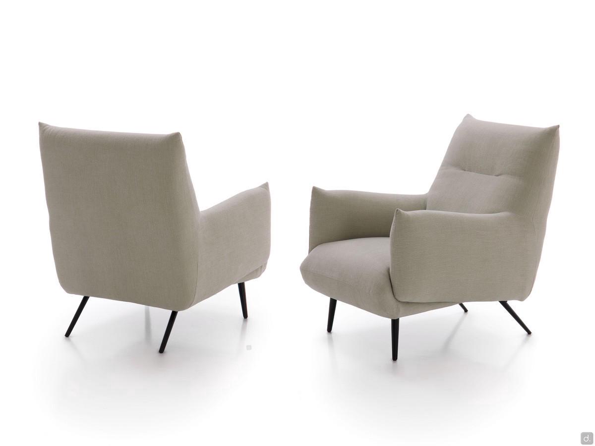 Fauteuil Tangeri caractérisé par des pieds métalliques hauts et fins et des volumes rembourrés recouverts de tissu, de similicuir, de velours ou de cuir.