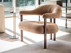 Fauteuil Greta de Cattelan, avec une structure métallique minimale et des accoudoirs enveloppants tapissés et recouverts d'un revêtement assorti à l'assise.