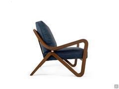 Fauteuil rembourré Jody avec structure caractéristique en bois massif courbé qui, tel un ruban, dessine le dossier, les accoudoirs et les pieds avant.