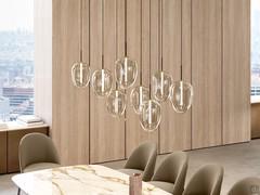 Suspension Guadalupe, ici proposée dans le modèle à 8 diffuseurs. Les abat-jours, tous identiques, sont en verre soufflé transparent et éclairés par une barre LED interne.