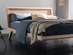 Lit en chêne massif avec tête de lit en bois Sebastian dans le modèle à effet "suspendu" avec pied avant formé par une plaque de verre extra-claire.