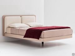 Lit de maître avec tête de lit Slim, légèrement plus large que le cadre de lit. L'effet de suspension du lit est donné par le pied central unique, réglable en hauteur jusqu'à +10 cm.