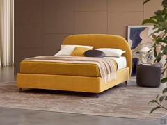 Lit en textile tapissé avec tête de lit Antilla incurvée, présenté ici avec anneau de lit h.25 légèrement surélevé par rapport au sol mais équipé d'un coffre de rangement