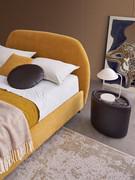 Détail du cadre de lit et de la tête de lit rembourrés au profil incurvé, recouverts de tissu jaune et disponibles dans de nombreuses autres variations