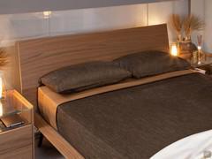 Vue de la tête de lit en plaqué bois de noyer canaletto en teinte au cadre de lit et aux commodes