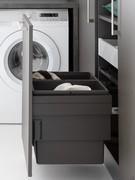 Détail de la porte coulissante avec panier à linge intégré dans la colonne ouverte de la buanderie Oasis L01