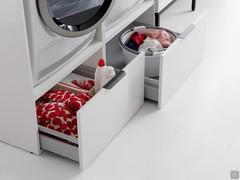 Détail des paniers sous les colonnes ouvertes du lave-linge et du sèche-linge, capables de supporter le poids des appareils grâce à une barre de soutien métallique invisible.