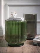 Le traitement plissé du verre donne un effet irisé, changeant et dynamique à la table basse, présentée ici dans la configuration avec un piètement laqué noir mat.