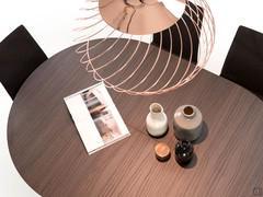 Détail du plateau (finition non disponible) qui se transforme de rond en ovale avec une rallonge intérieure pliable.