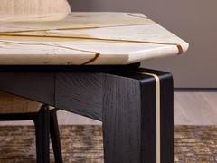 Détail de la base de la table Lewis, en chêne noir massif avec un insert central en métal Sand Gold. On remarque également la forme particulière du plateau, dont les bords suivent la forme de la base.