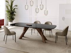Table à pieds croisés en bois de Palladium dans la version tonneau avec un plateau en verre moulé, caractérisé par une surface légèrement ondulée et irrégulière (mais lisse au toucher). Disponible en différentes couleurs