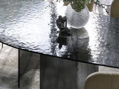 Détail de la texture du verre martelé. Le travail génère un effet d'ondulation qui reflète la lumière environnante de manière irisée.