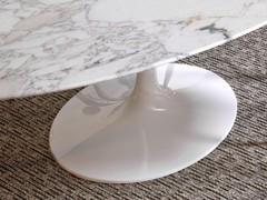 Détail des formes sinueuses de la tige et de la base elliptique en aluminium laqué blanc brillant