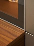 Particolare della giunzione tra la base sospesa in noce canaletto, la colonna battente laccata opaca e il telaio della vetrina laccato in tinta a quest'ultima