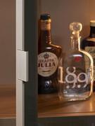 Dettaglio della maniglia in metallo incassata nel telaio della vetrina, laccata in tinta a quest'ultimo per un aspetto pulito e minimale