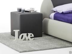 Pouf in similpelle Cherie usato a fianco del letto come piano di appoggio