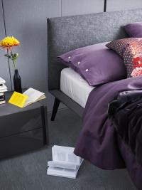 Détail de la tête de lit revêtue en tissu et du cadre de lit en laqué mat Plomb