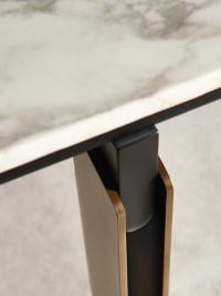 Détail en gros plan des pieds de la table Mirage de Cantori dans la version tonneau : le sous plateau en bois laqué noir relie le pied en bronze et le plateau en marbre