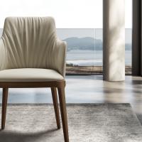 Vue de face de la chaise rembourrée avec dossier interne plissé Michela, avec accoudoirs (fauteuil). Revêtement en cuir et pieds en bois massif de frêne Noyer Canaletto.