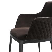 Vue de côté de la chaise salon rembourrée avec dossier externe matelassé Michela avec accoudoirs (fauteuil). Revêtement en cuir et pieds en bois massif de frêne teint Noir.