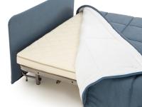 Détail de la tête de lit revêtue en tissu et du revêtement du canapé transformable en couette