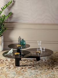 Table d'appoint avec trois plateaux Cosmo caractérisé par : structure en frêne noir, plateaux en verre fumé transparent, et cercle central en métal laqué or mat.