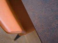 Dettaglio piano del tavolo in vetro ceramica opaca Ossido Bruno e della sedia in pelle