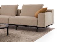 Dettaglio dei volumi del divano Cassis in appoggio su un basamento in legno alto da terra