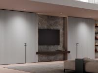 Boiserie per tv con illuminazione integrata Lounge: gli schienali a muro sono in pietra ceramica Laminam pietra grey.