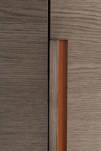 Particolare della maniglia integrata in legno essenza rovere argilla con fondo in contrasto laccato opaco cuoio